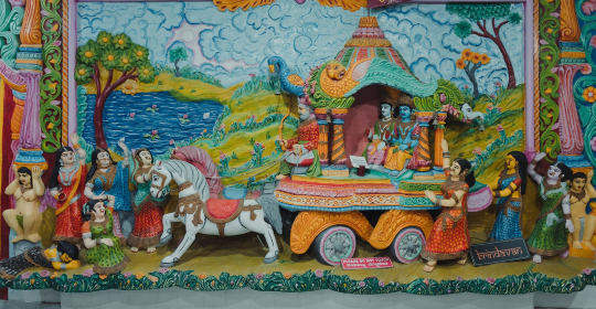 A large stucco sculpture with Lord Krishna and Balarama being taken by Akrura in a chariot to meet their evil uncle Kamsa